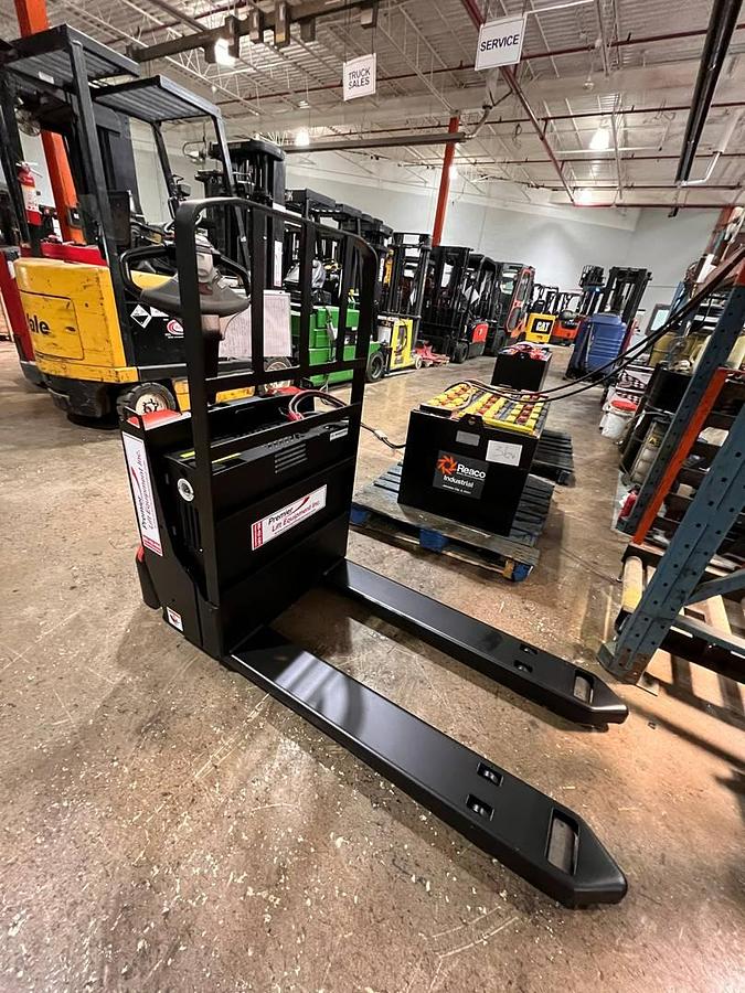 Raymond 8210 – angled front view – tapered 27×45 forks leading to chassis and tiller head – CSA/MOL certified electric walkie pallet jack – Brampton ON