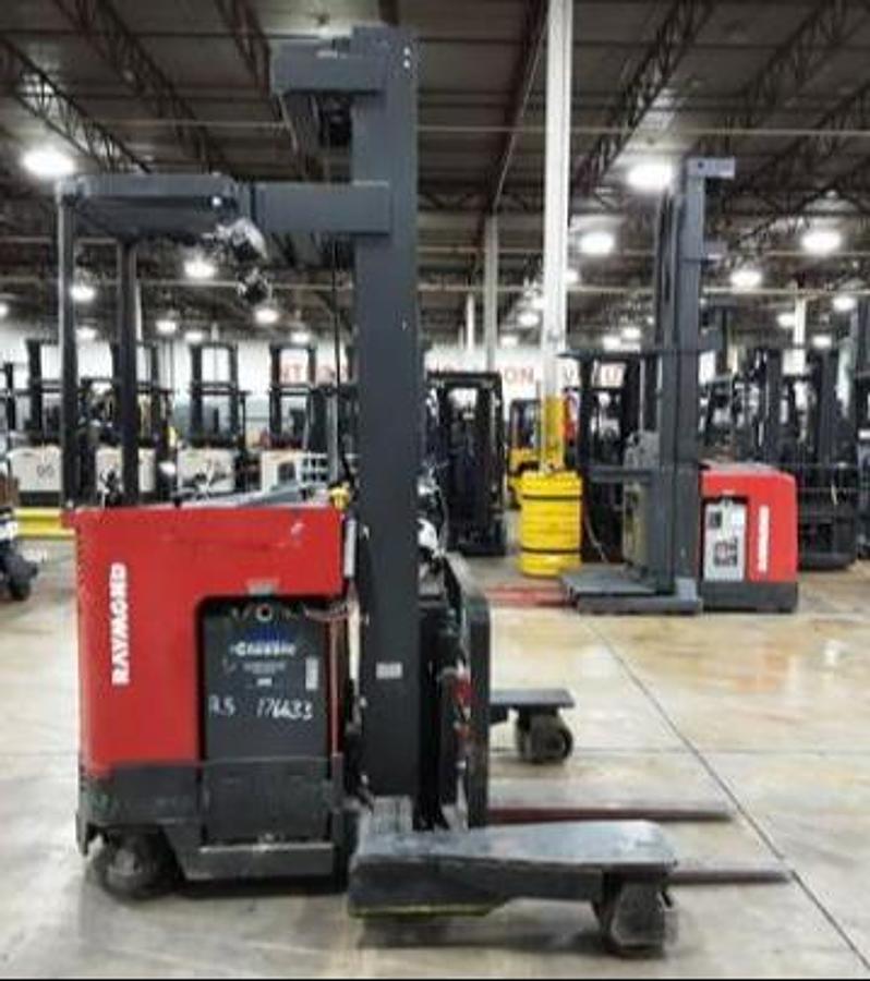 Side profile of 2012 Raymond EASI 4DR-45TT electric reach truck showing directional wheels, mast rails, and narrow aisle chassis during Brampton deployment