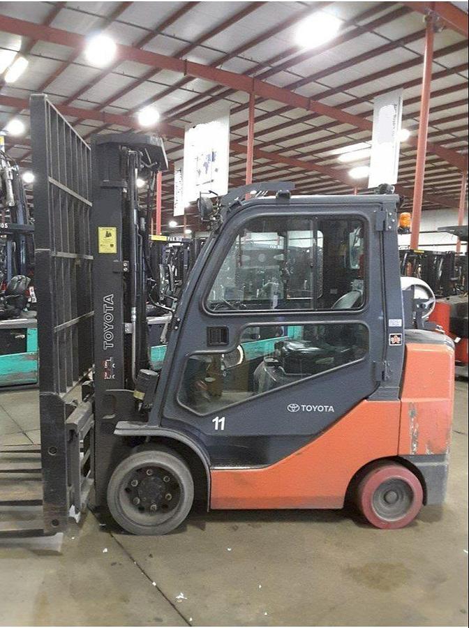 Side view of refurbished 2011 Toyota 8FGCU32 LP gas forklift showing full cab enclosure, rear chassis, and CSA decal during Brampton deployment