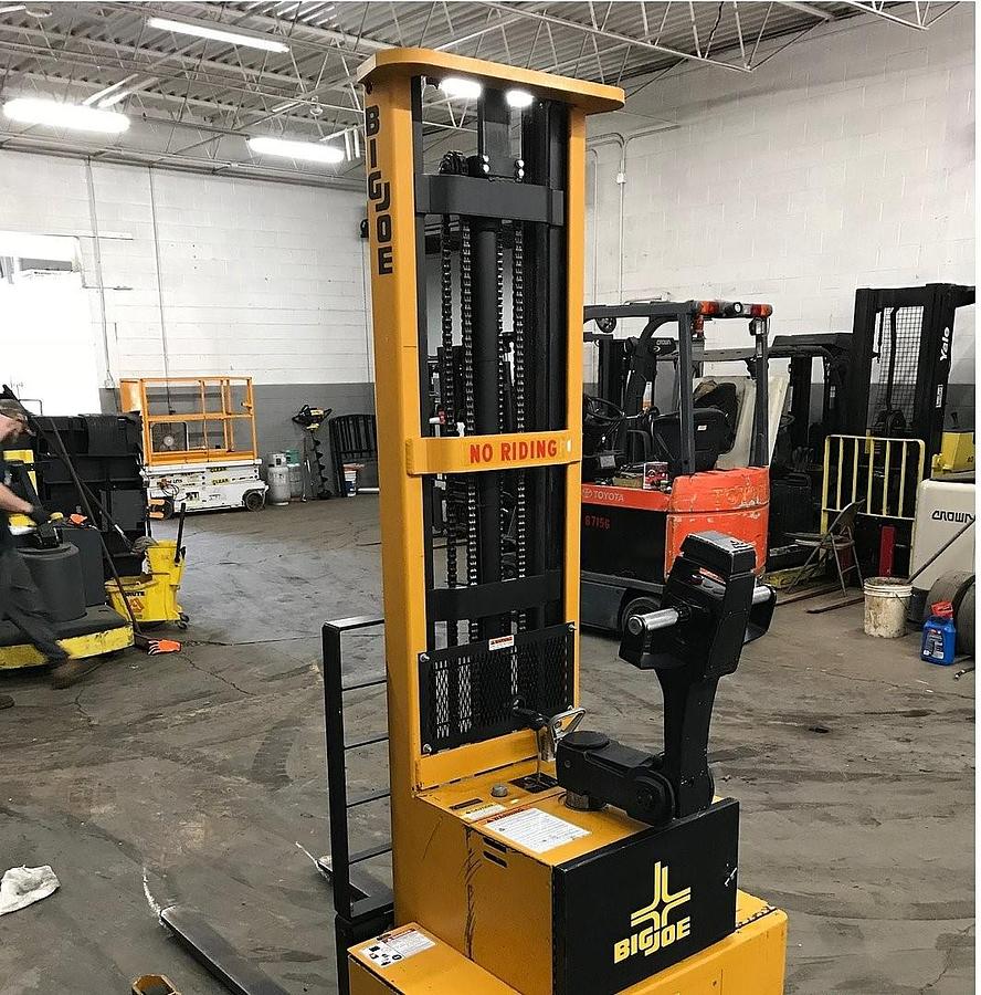 Rear side view of refurbished 2005 Big Joe PDM‑30 electric walkie straddle stacker showing rear chassis, 12 volt battery compartment, and CSA certification decal during Ontario deployment.