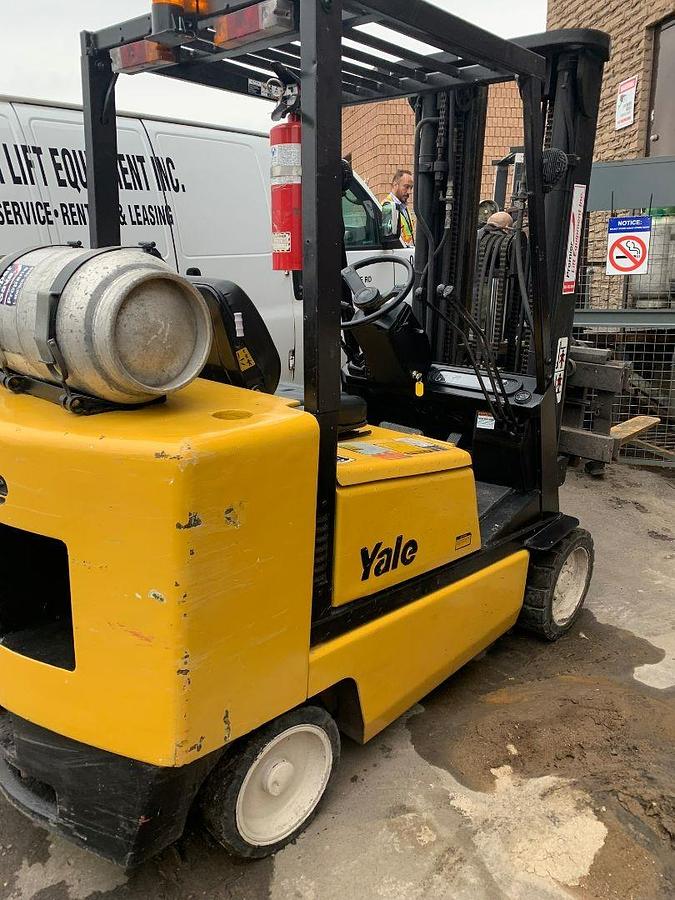 Rear view of vintage refurbished 2004 Yale GLC050DEJUA083 LPG cushion forklift showing counterweight, rear tires, and propane tank bracket during Brampton deployment