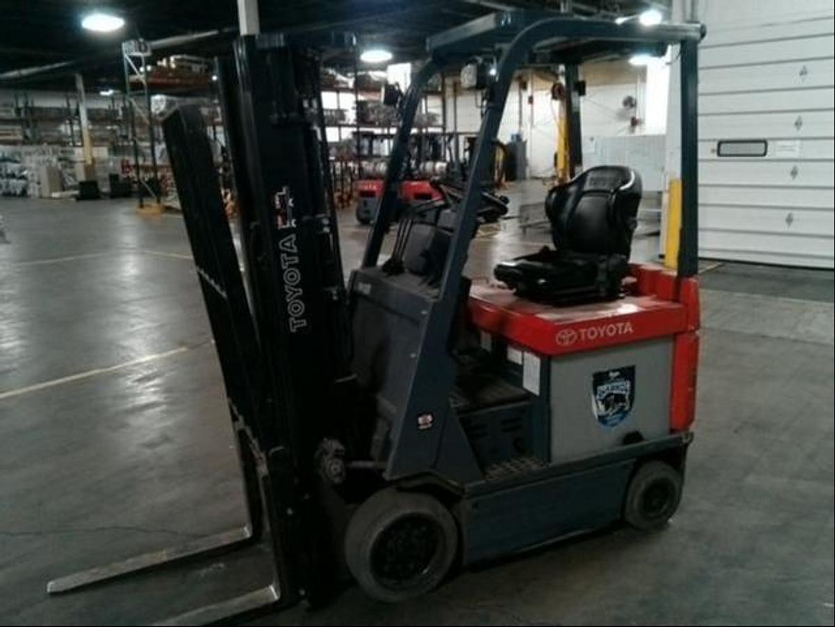 Side view of refurbished 2013 Toyota 7FBCU15 electric 4-wheel sit-down forklift showing triple mast, CSA decal, and side shift carriage during Ontario deployment