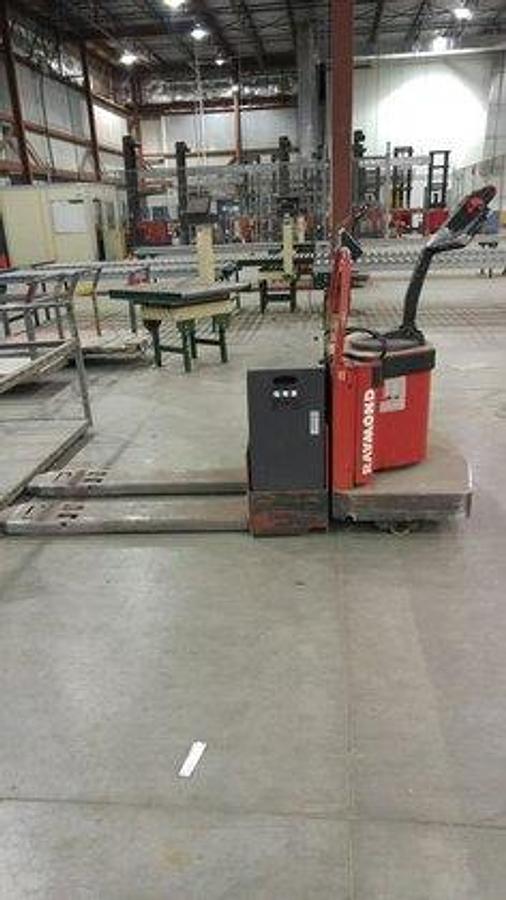 Opposite side view of refurbished 1996 Raymond 112-FRE60L electric walkie/rider pallet jack showing drive unit cover, fork tips, and rider platform during Ontario deployment