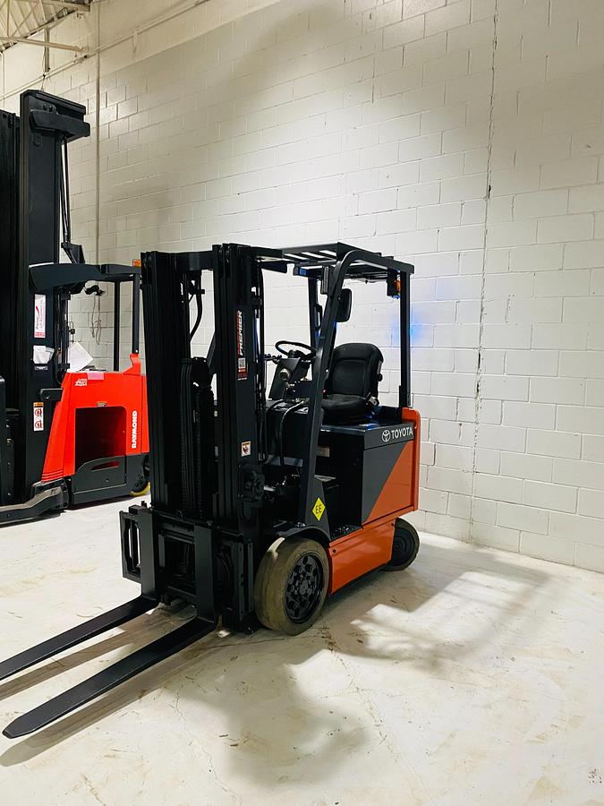 Opposite angled side view of Toyota 8FBCU20 COM electric sit-down forklift showing side shift carriage, mast tilt cylinders, and CSA-certified frame – unit staged in Brampton ON