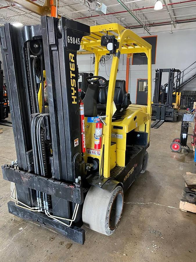 Opposite front side view of refurbished 2019 Hyster E120XN electric forklift showing counterweight, cab enclosure, 83"/169" triple mast, solid tires, and CSA certification decal during Ontario deployment.