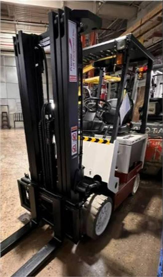 Front angled view of refurbished Nissan CWPG2L25S electric 4‑wheel forklift showing 188" triple mast, 48 volt chassis, and CSA certification decal during Brampton deployment.