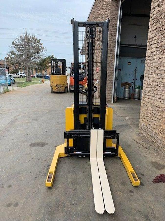 Front view of refurbished 2003 Yale MSW040 electric walkie straddle stacker showing fork carriage, mast extension, and tilt cylinders during Ontario deployment