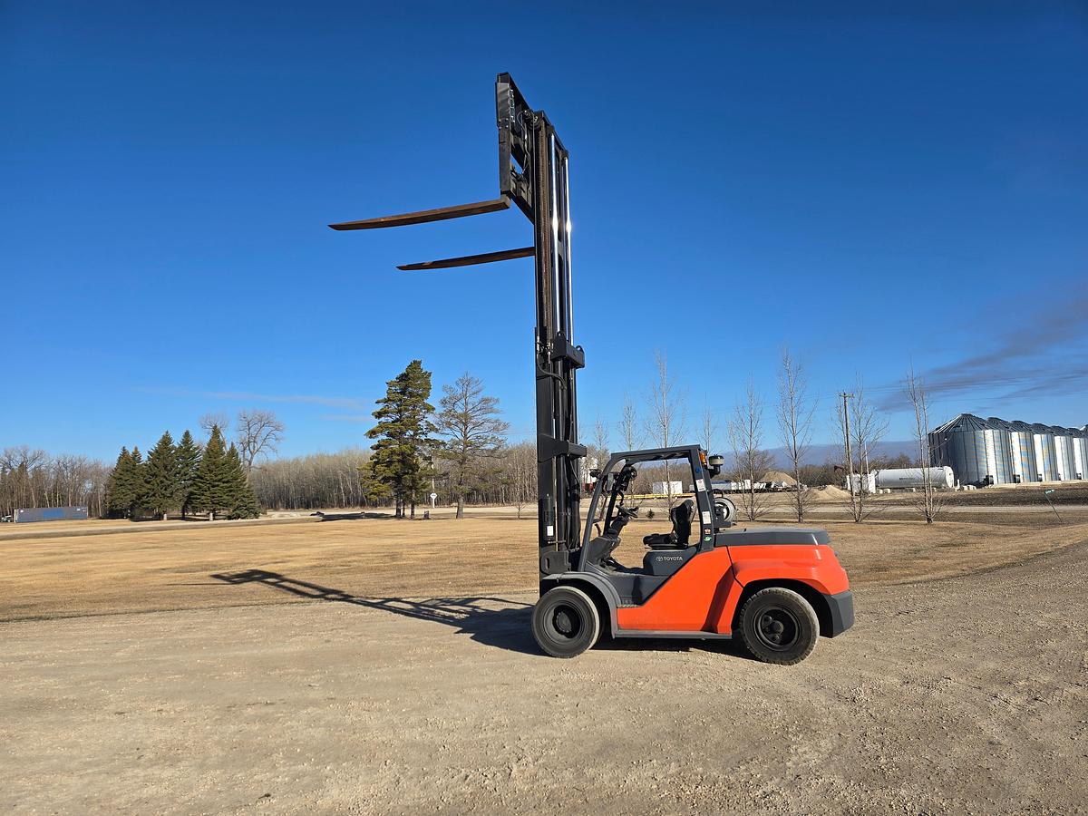 Forks Raised Side view of CSA-certified Toyota 8FG80U propane forklift with two-stage mast and fork positioner – staged in Manitoba yard