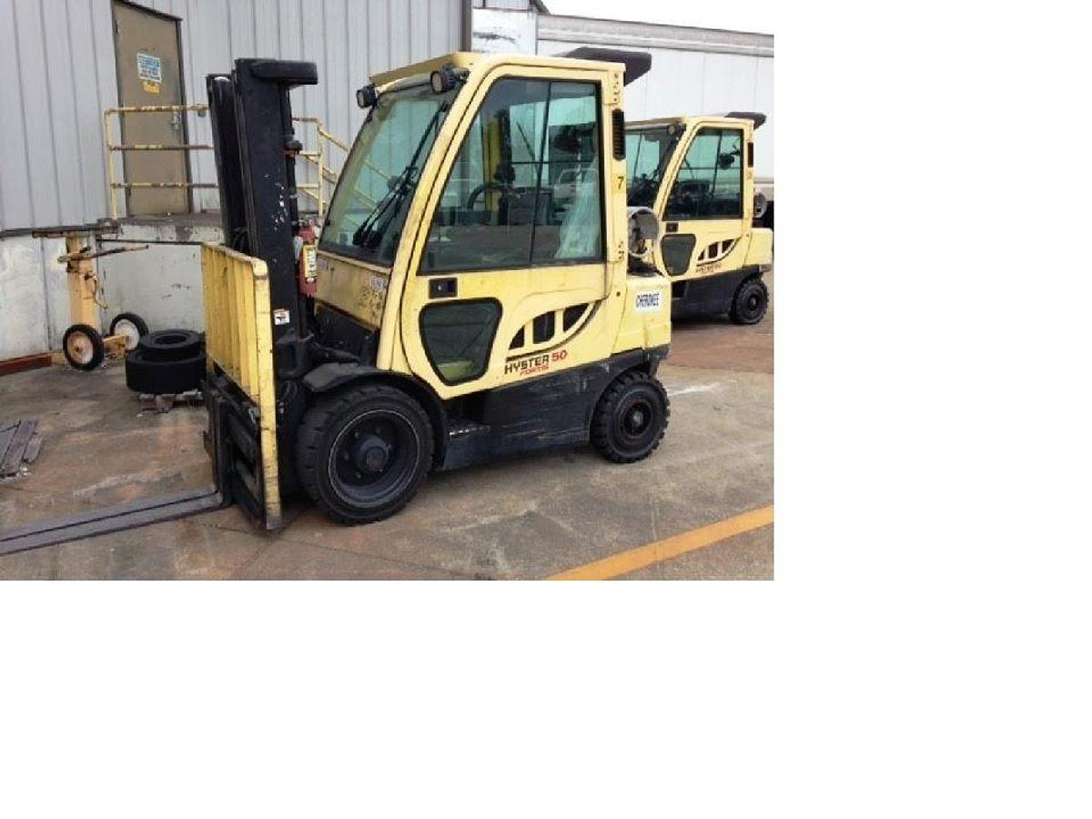 Side view of refurbished 2011 Hyster H50FT LP Gas forklift showing full cab, solid pneumatic tires, side shift, fork positioner, and CSA certification decal during Ontario deployment.