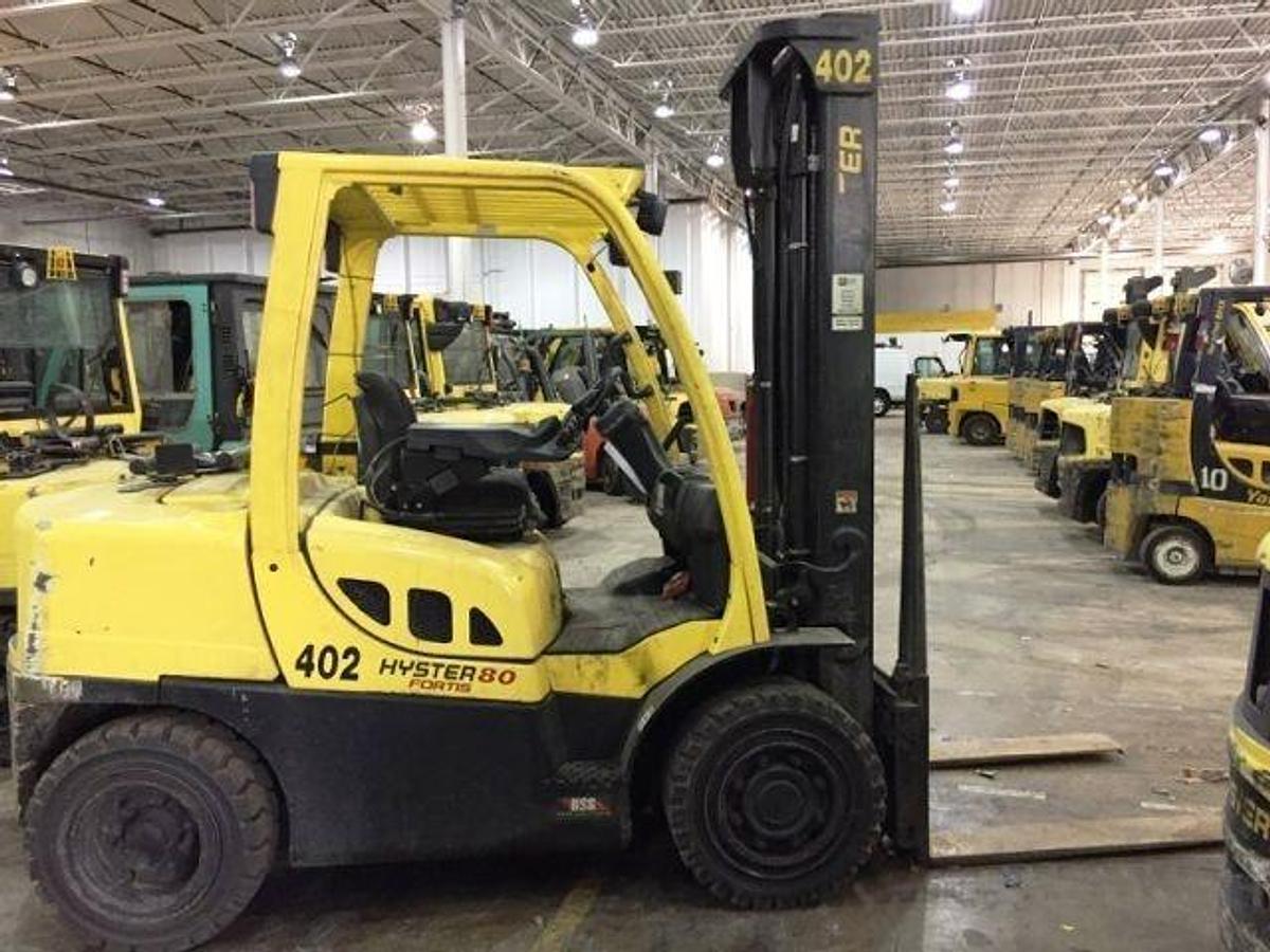 Side profile of 2013 Hyster H80FT propane forklift showing mast rails, chassis layout, and pneumatic tires during Brampton deployment
