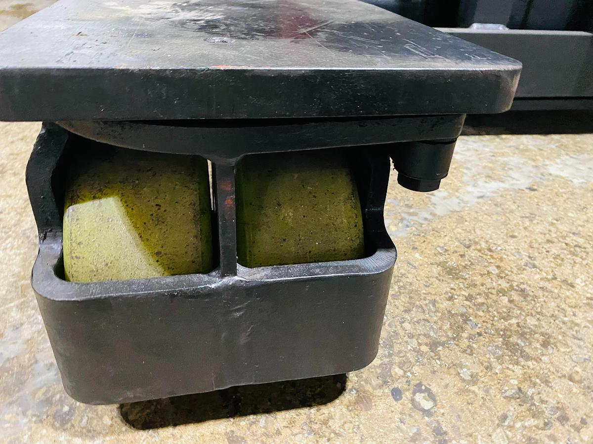 Close-up of front legs on Raymond EASI 4D-R45TT electric reach truck showing newly installed poly caster wheels and directional steering assembly during Brampton deployment