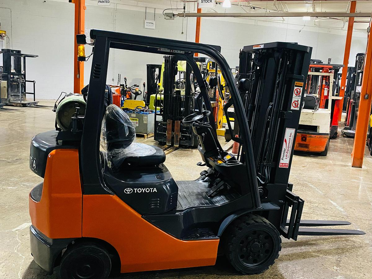 Opposite side view of 2019 Toyota 8FGCU20 propane forklift – CSA-certified 3,400 lb cushion tire chassis showing operator station, propane tank bracket, and traction tires with safety decals applied, Brampton ON – Premier Lift Equipment