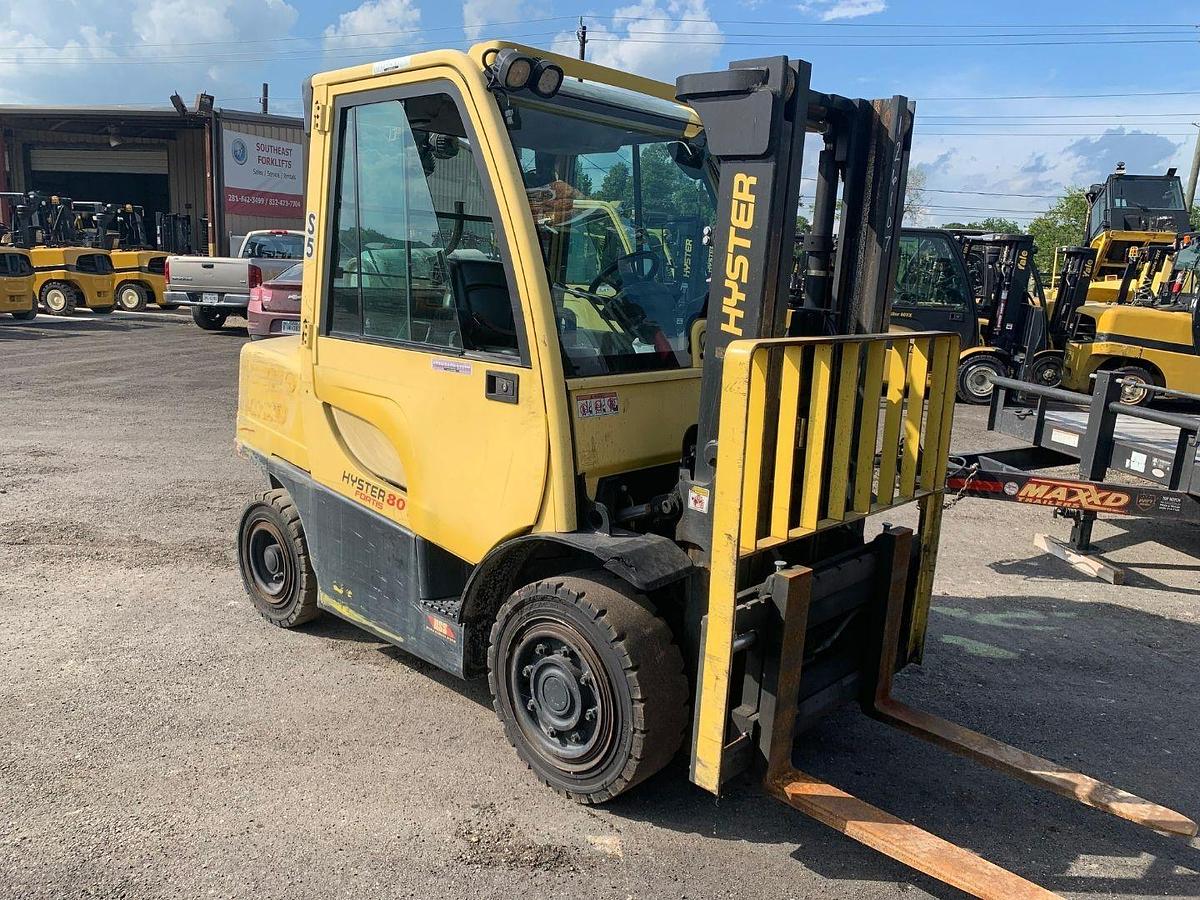 Side view of refurbished 2015 Hyster H80FT LP Gas forklift showing full cab with heat, solid pneumatic tires, and 2‑stage mast with full free lift and side shift during Ontario deployment.