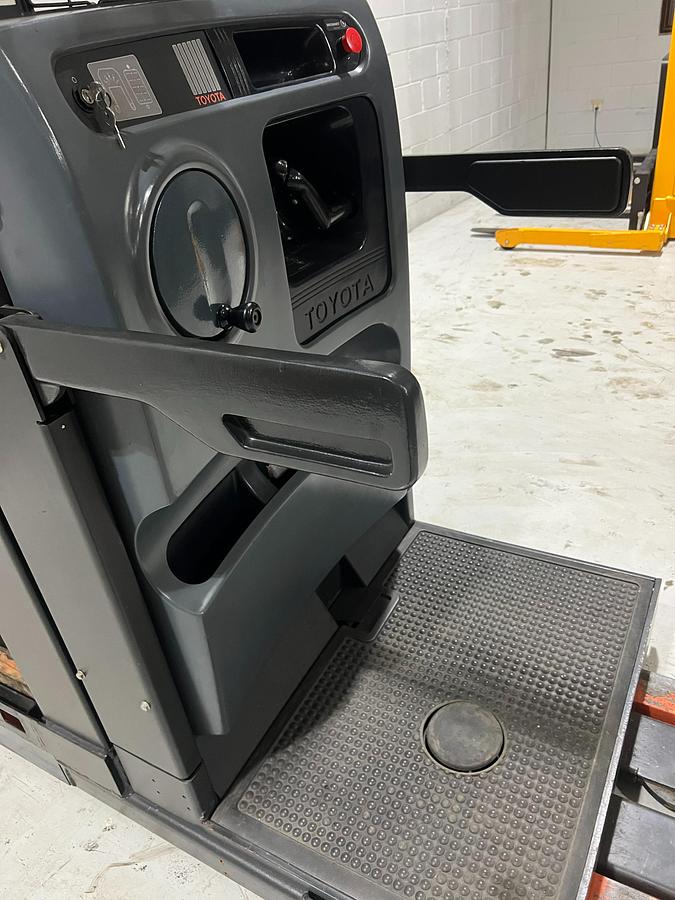 Angled operator view of Budget Toyota 7BPUE15 order picker showing safety arms and platform guard system.
