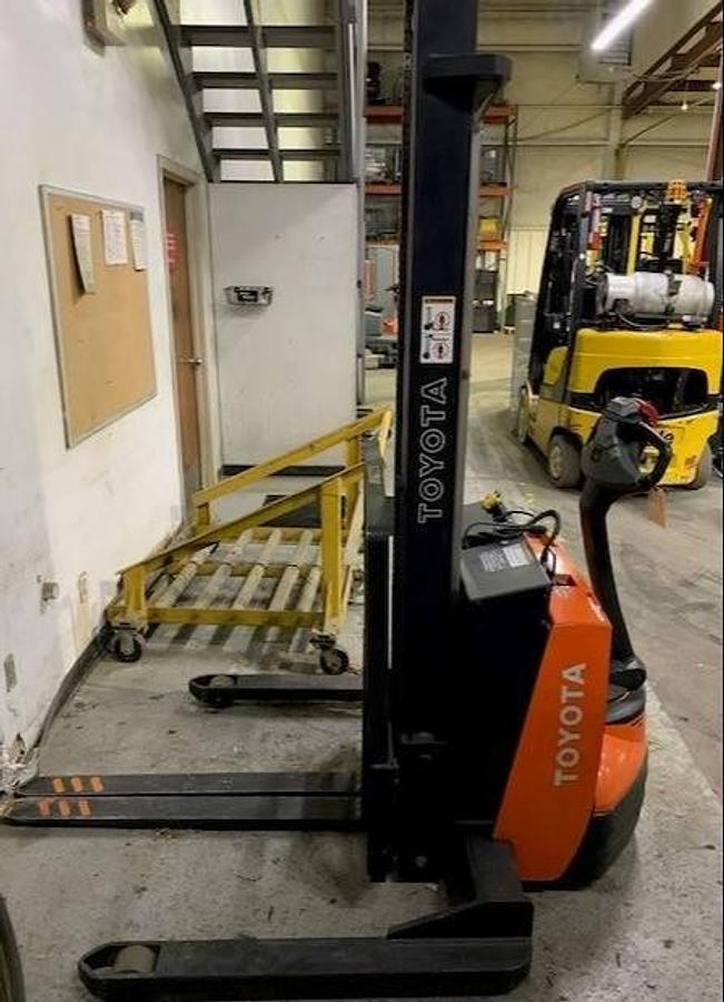 Side view of refurbished 2014 Toyota 7BWS10 electric walkie straddle stacker showing two-stage mast, CSA decal, and compact chassis during Ontario deployment