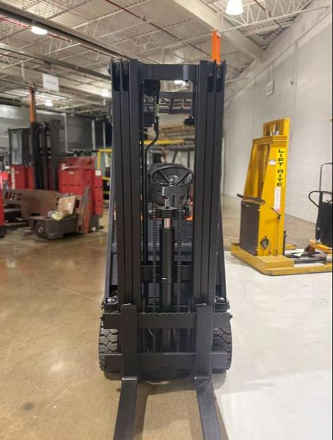 Front view of refurbished 1996 Toyota 5FBCU15 vintage electric 4-wheel sit-down forklift showing fork carriage, mast rails, and tilt cylinders during Ontario deployment