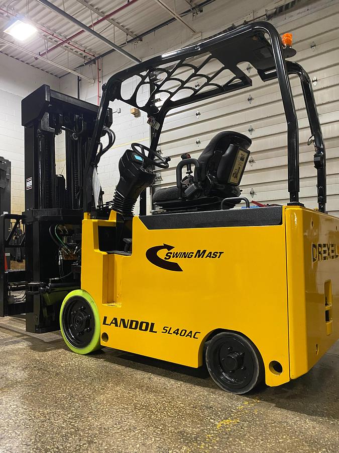Front side angle of Drexel SL-40AC SwingMast forklift showing 250" quad mast, pivoting carriage, directional wheels, and narrow aisle chassis during Brampton deployment
