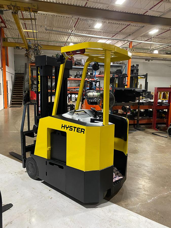Rear-left angle view of Hyster E30FR-24 electric dockstocker showing stand-up rider platform, rear-wheel drive, battery compartment, and CSA-certified chassis – unit staged in Brampton ON
