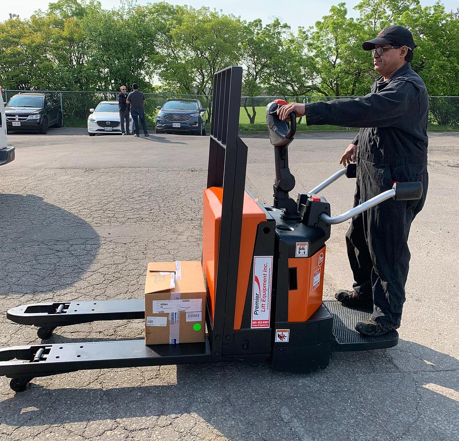 2023 BT LPE200Z side view with operator – platform down – hybrid walkie/rider operation – CSA‑ready electric pallet jack