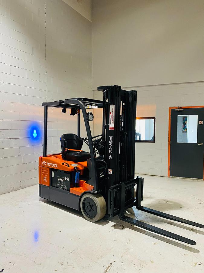 Front angle view of 2015 Toyota 7FBEU15 electric forklift showing extended forks, triple-stage mast, load backrest, and CSA-certified chassis – unit staged in Brampton ON