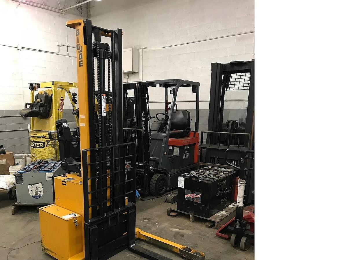Front angled view of refurbished 2005 Big Joe PDM‑30 electric walkie straddle stacker showing forks, mast, straddle legs, battery compartment, and CSA certification decal during Ontario deployment.
