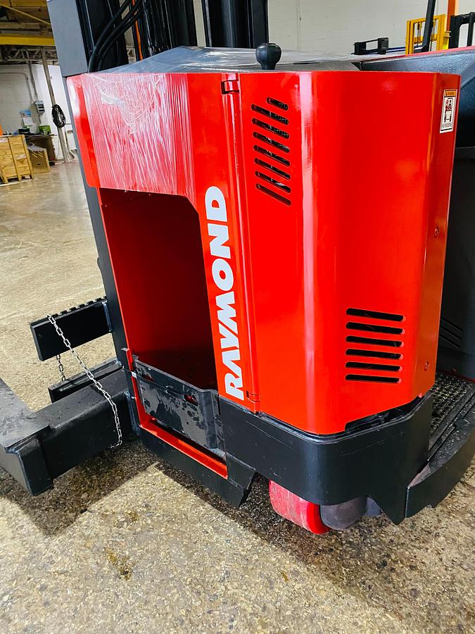 Opposite side close-up of Raymond EASI 4D-R45TT electric reach truck showing open battery compartment, battery rollers, and CSA compliance tag during Brampton deployment