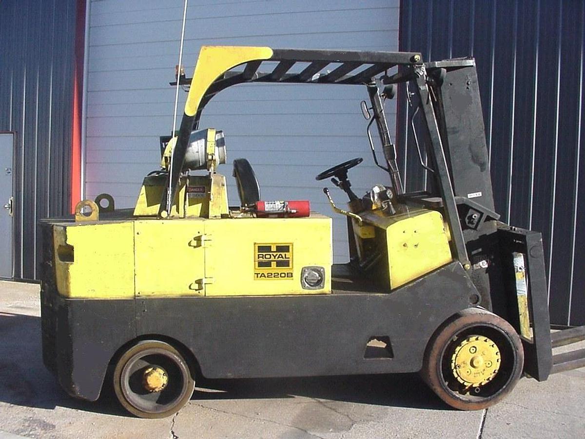 High‑capacity LPG cushion tire forklift, 15,000 lb+ indoor model with solid non‑marking tires, heavy‑duty mast, overhead guard, and enclosed cab operating in a warehouse environment.