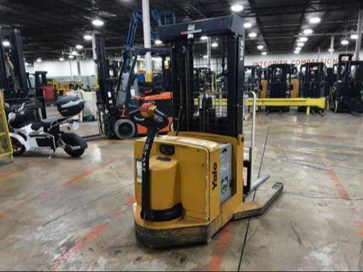 Rear angle side view of refurbished 2011 Yale MR03030 electric walkie reach stacker showing operator handle, battery compartment, and rear wheels during Ontario deployment