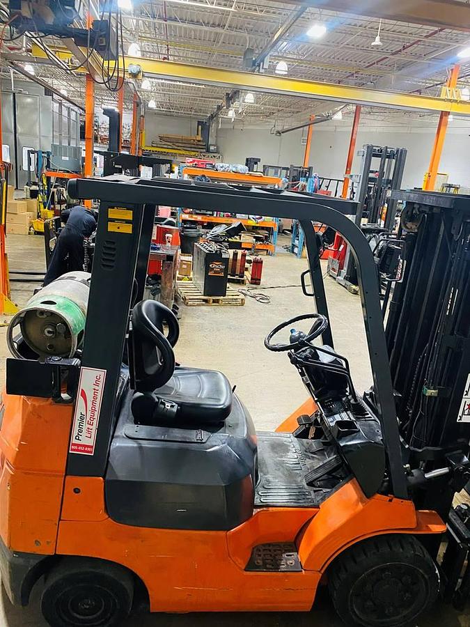 Opposite side view of vintage refurbished 2001 Toyota 7FGCU25 LP gas forklift showing operator cab, rear chassis, and CSA decal during Brampton deployment