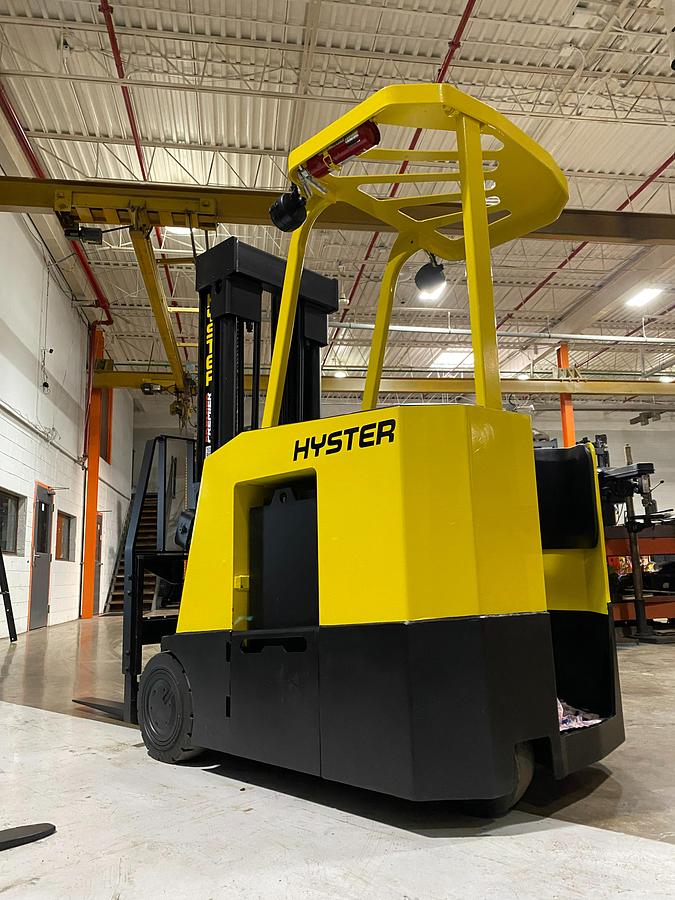 Rear-left angle view of Hyster E30FR-24 electric dockstocker showing stand-up rider platform, rear-wheel drive, battery compartment, and CSA-certified chassis – unit staged in GTA ON