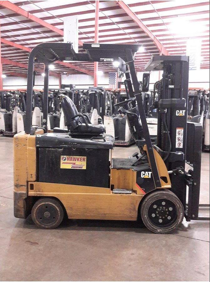 Side view of refurbished 2012 Cat E6000 4‑wheel electric forklift showing 48 volt chassis, load backrest, solid tires, 3‑stage mast with side shift, and CSA certification decal during Brampton deployment.