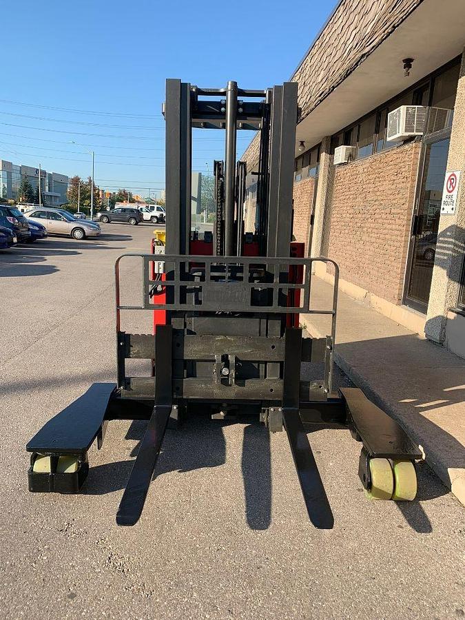 Head-on view of Raymond electric reach truck showing base legs, triple mast, forks, and carriage assembly with CSA safety decals visible during Brampton deployment