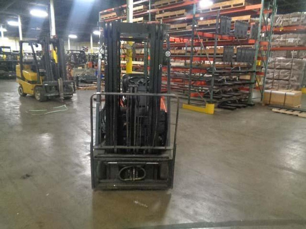 Head-on view of 2012 Toyota 7FBEU20 electric forklift with forks lowered, triple mast extended, and CSA safety markings visible