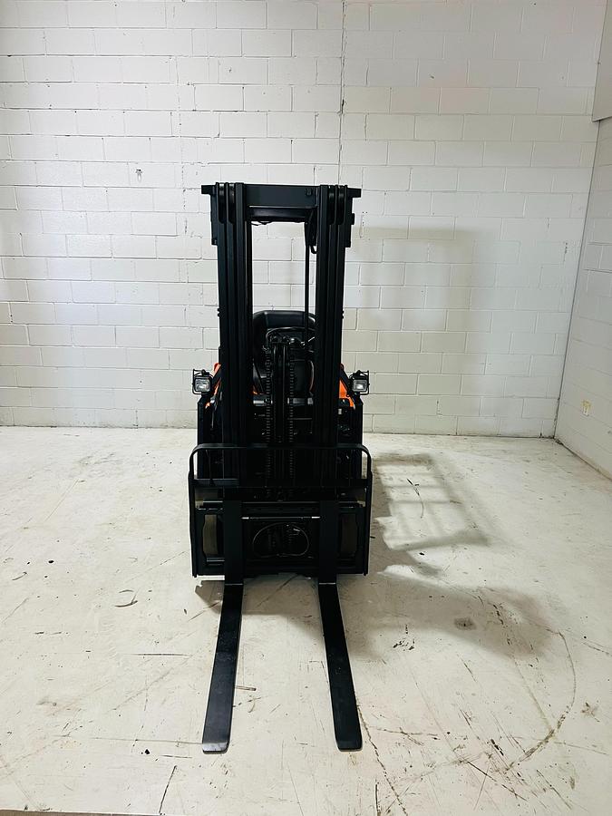 Head-on view of 2014 Toyota 7FBEU15 electric forklift with forks lowered, triple mast extended, and CSA safety markings visible