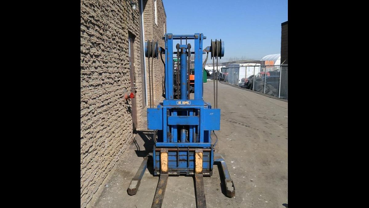 Front view of refurbished 1995 Blue Giant NA120W30 electric walkie straddle stacker reach showing straddle legs, mast, 42" forks, and CSA certification decal during Brampton deployment.