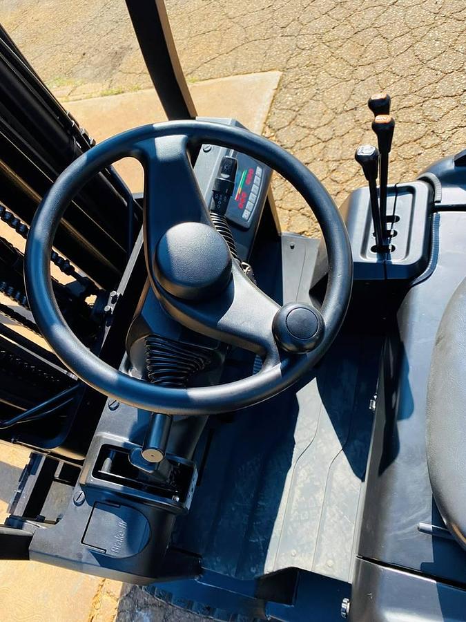 Operator compartment of refurbished 2018 EP Equipment CPD20 3‑wheel electric forklift showing steering wheel, electric controls, solid pneumatic tires, 3‑stage mast, and CSA certification decal during Brampton deployment.