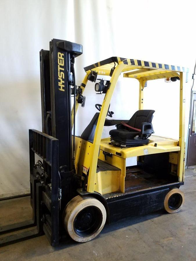 Opposite side view of refurbished 2015 Hyster E70XN electric forklift showing counterweight, cab enclosure, 54" forks, side shift fork positioner, new battery compartment, solid tires, and CSA certification decal during Ontario deployment.