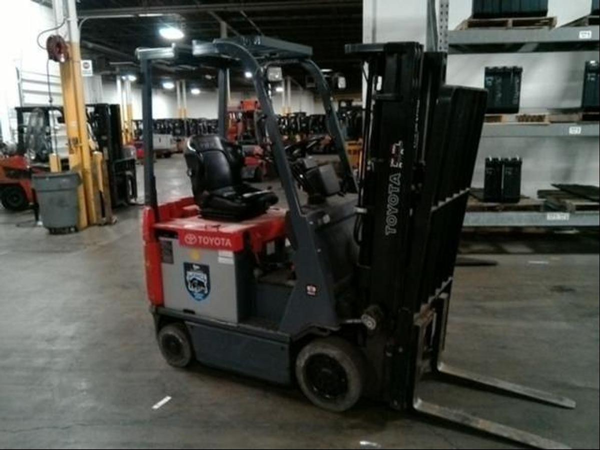 Front angle side view of refurbished 2013 Toyota 7FBCU15 electric 4-wheel sit-down forklift showing fork tips, mast extension, and CSA certification decal during Ontario deployment