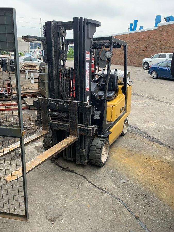 Opposite angle front side view of vintage refurbished 2004 Yale GLC050DEJUA083 LPG cushion forklift showing triple mast, side shift carriage, and operator cab during Brampton deployment