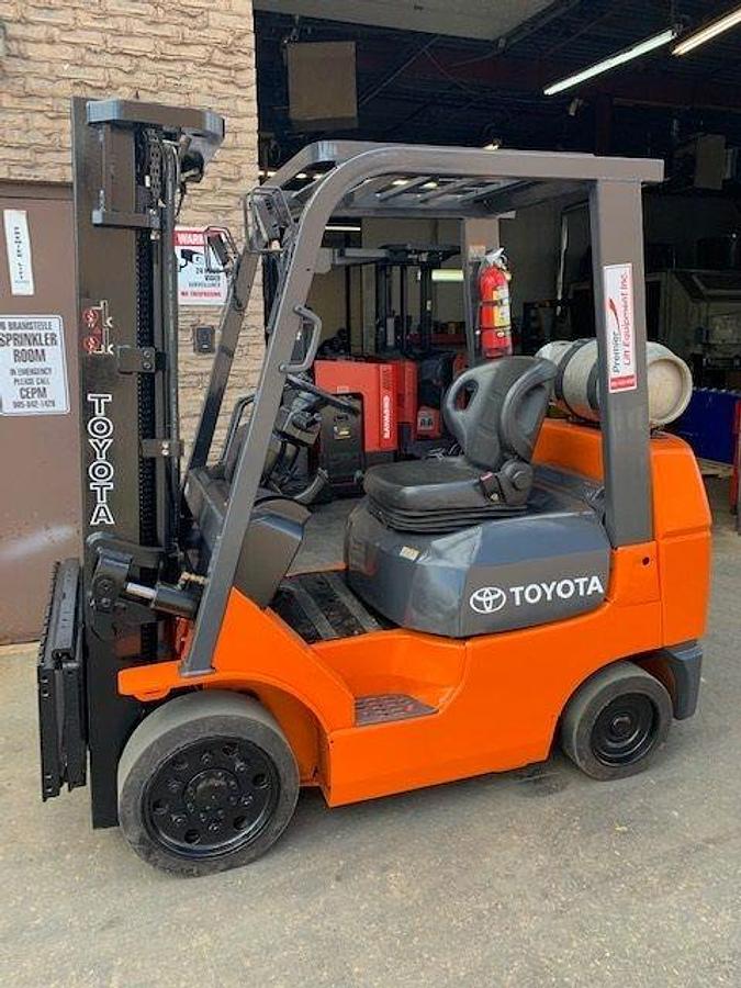 Front side view of refurbished 2006 Toyota 7FGCU25 LP gas forklift showing triple mast, 42" forks, and black smooth cushion tires during Brampton deployment