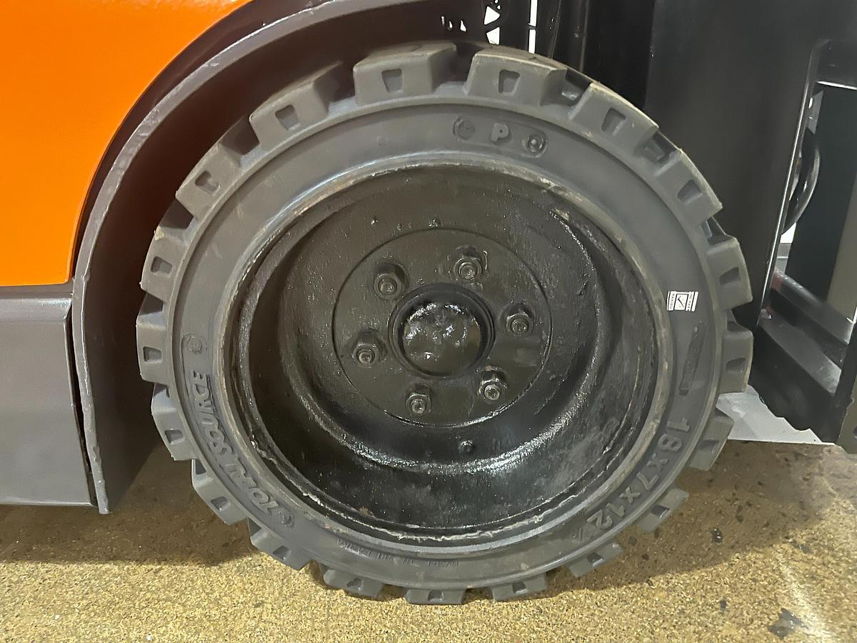 Front drive tire of Budget Toyota 5FBE18 — cushion tire and lower chassis detail.