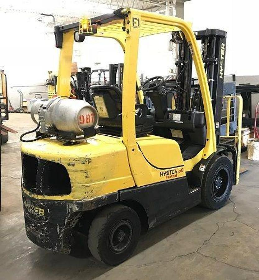 Rear side view of refurbished 2011 Hyster H60FT LP Gas forklift showing rear chassis, solid pneumatic tires, and safety lighting during Ontario deployment.