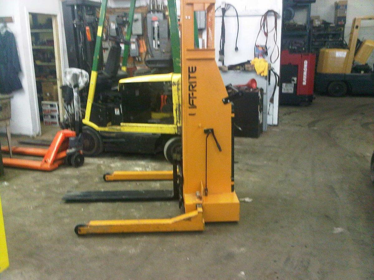Side view of refurbished 2010 Lift‑Rite T90K4024A manual push electric lift stacker showing forks, adjustable straddle legs, 12 volt battery compartment, and CSA certification decal during Ontario deployment.