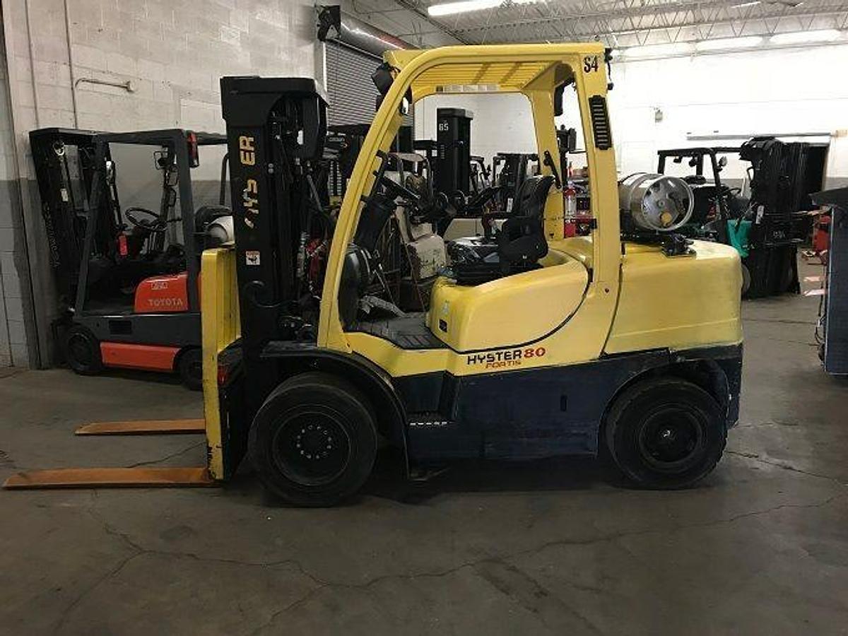 Opposite side view of refurbished 2011 Hyster H80FT LP Gas forklift showing counterweight, cab enclosure, and CSA certification decal during Ontario deployment.