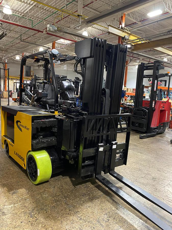 Head-on view of refurbished 2017 Drexel SL-40AC electric SwingMast forklift showing 89" collapsed quad mast, forks, base legs, and operator cab with CSA safety decals during Brampton deployment