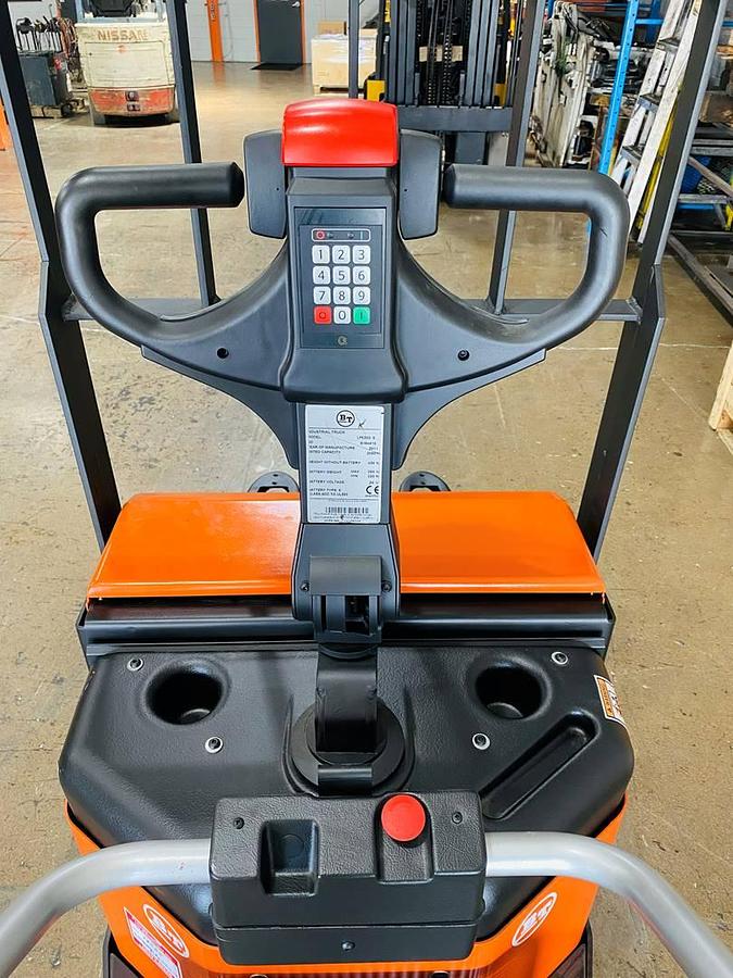 Operator compartment of refurbished 2016 BT LPE200/8 electric walkie/rider pallet jack showing steering handle, electric controls, flip‑down operator platform, load backrest, and CSA certification decal during Ontario deployment.
