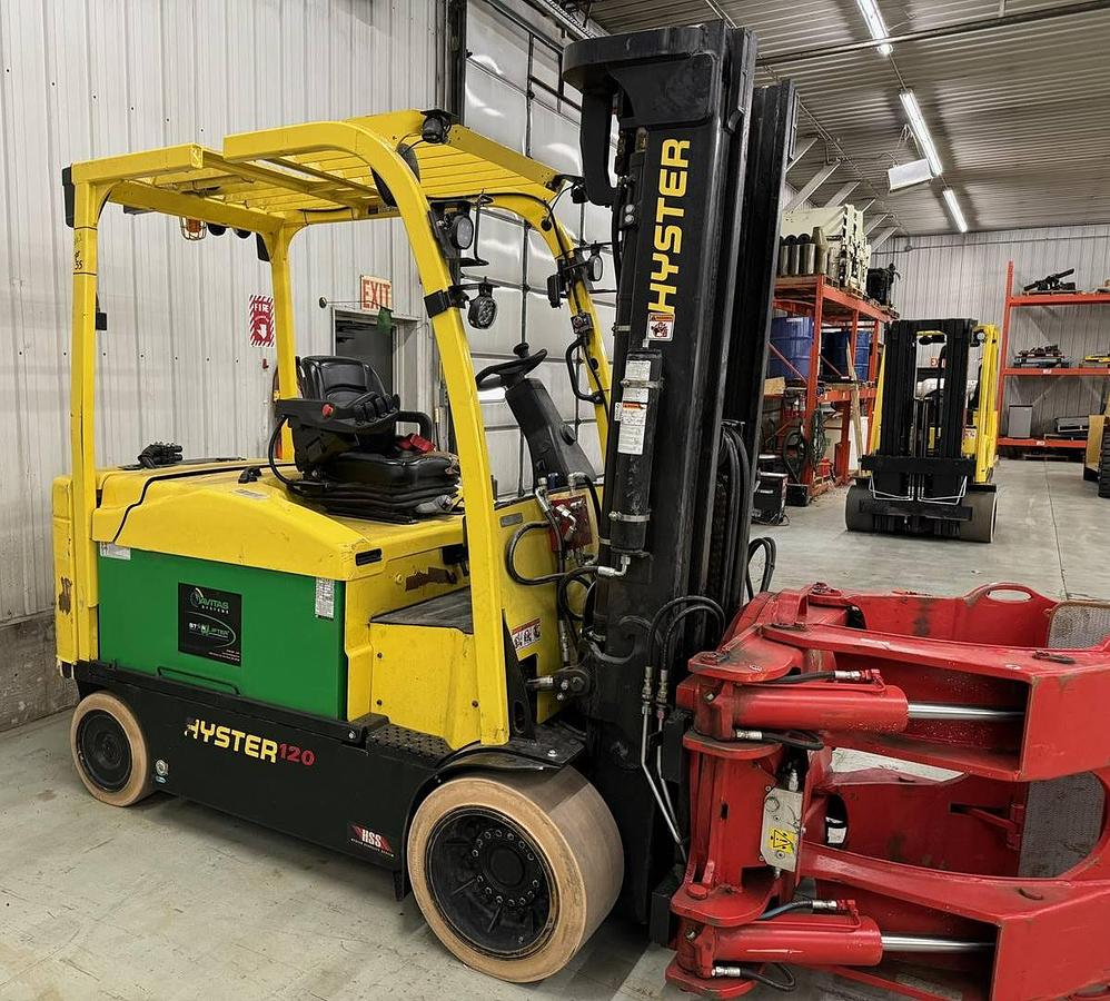 Opposite front side view of refurbished 2020 Hyster E120XN electric forklift showing counterweight, cab enclosure, paper roll clamp, 100"/209" quad mast, non‑marking tires, and CSA certification decal during Ontario deployment.