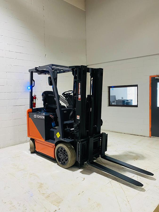 Front angled side view of Toyota 8FBCU20 COM electric sit-down forklift showing mast rails, fork tips, and CSA-certified chassis – unit staged in Brampton ON