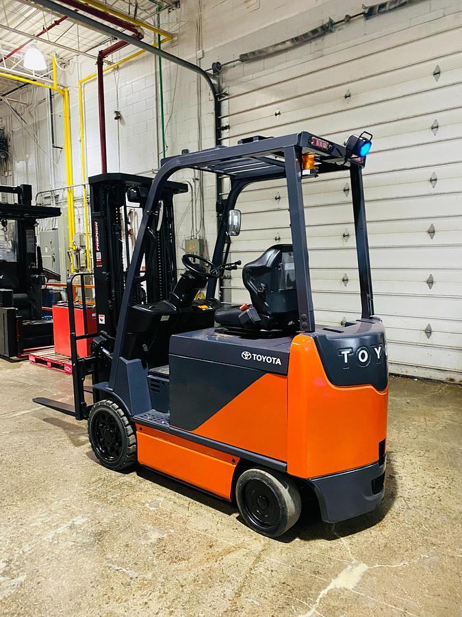 Rear side angle view of 2020 Toyota 8FBCU32-EE electric forklift showing counterweight, triple mast profile, and EE/CSA decals during Brampton deployment