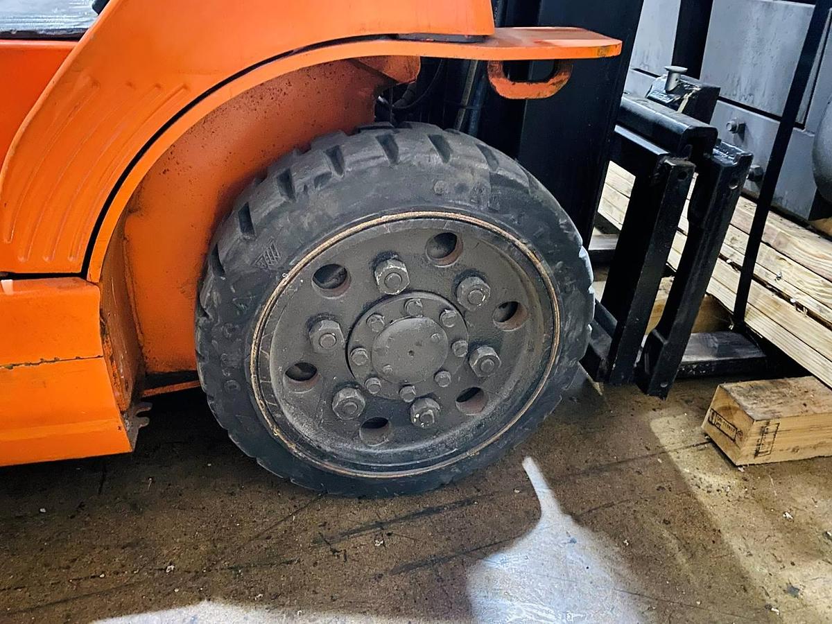 Close-up of traction drive tire on refurbished Toyota LP gas forklift showing deep tread pattern for indoor grip during Brampton deployment